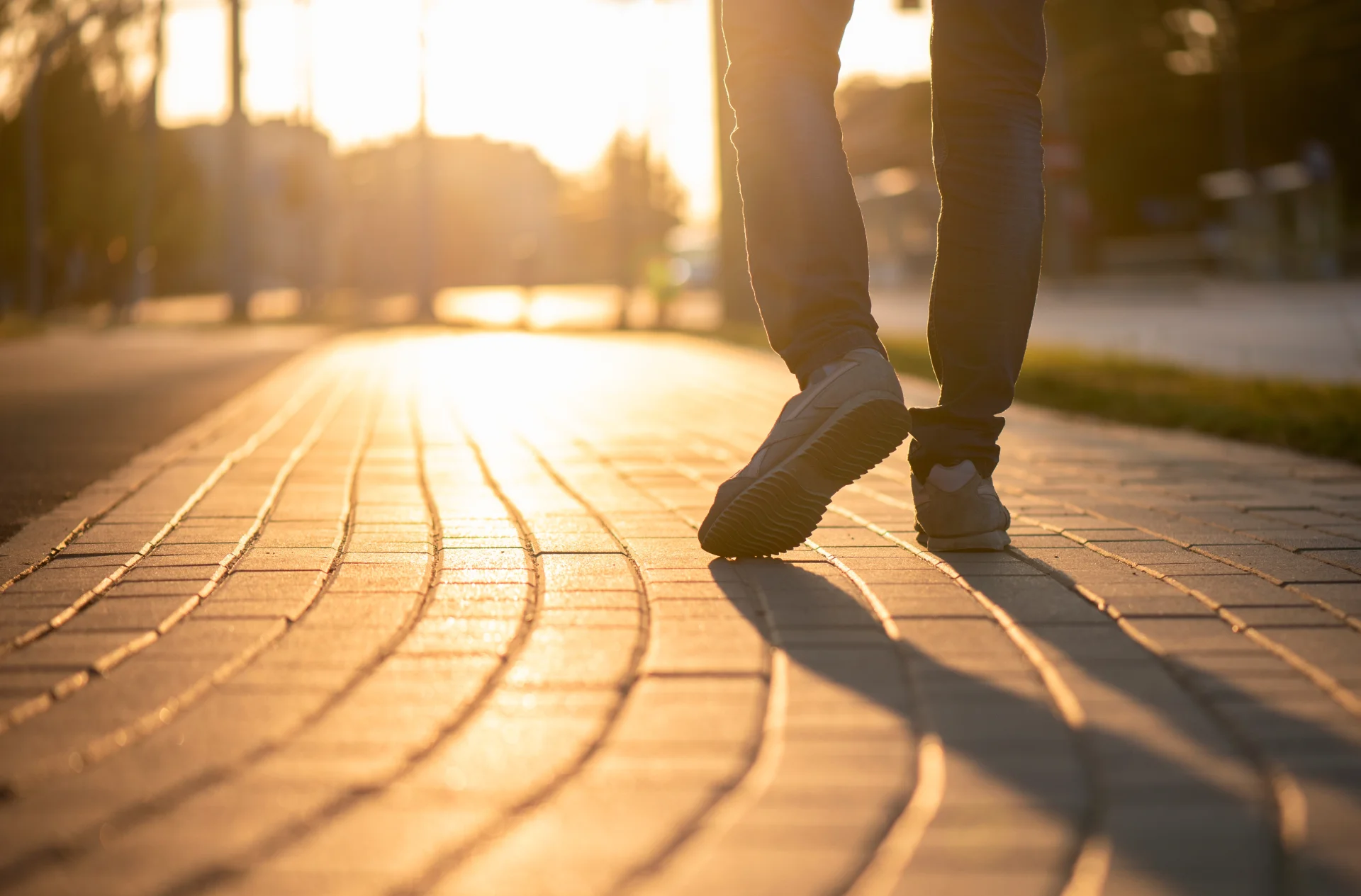 Person walking on a sunlit pathway, symbolizing stress relief and personal growth in the context of Evening Intensive Outpatient Programs for addiction recovery.