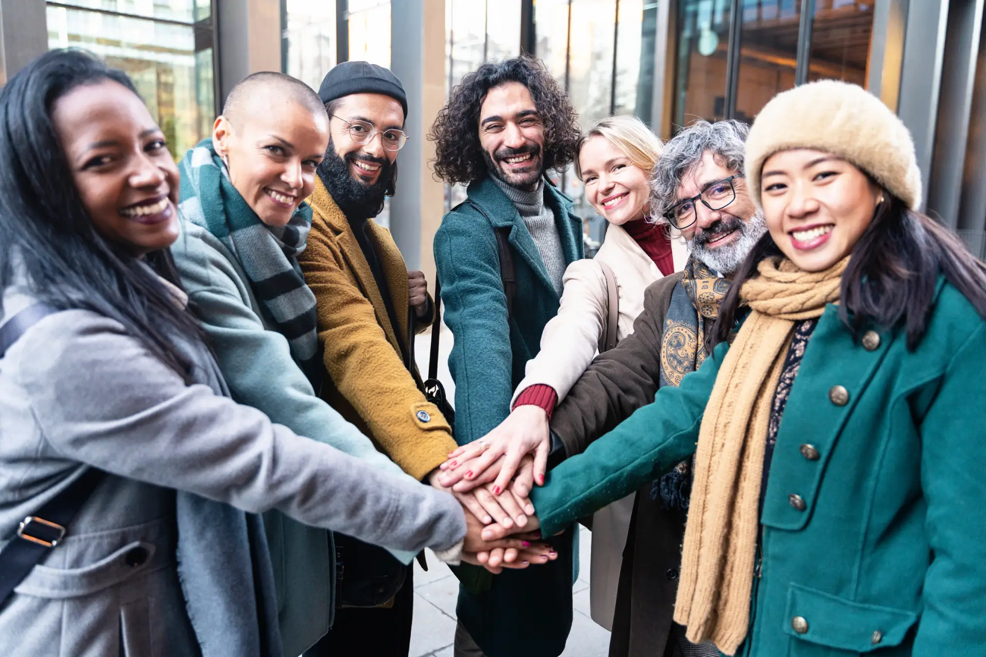 Diverse group of people smiling and stacking hands together, symbolizing support and community in addiction recovery on Long Island.
