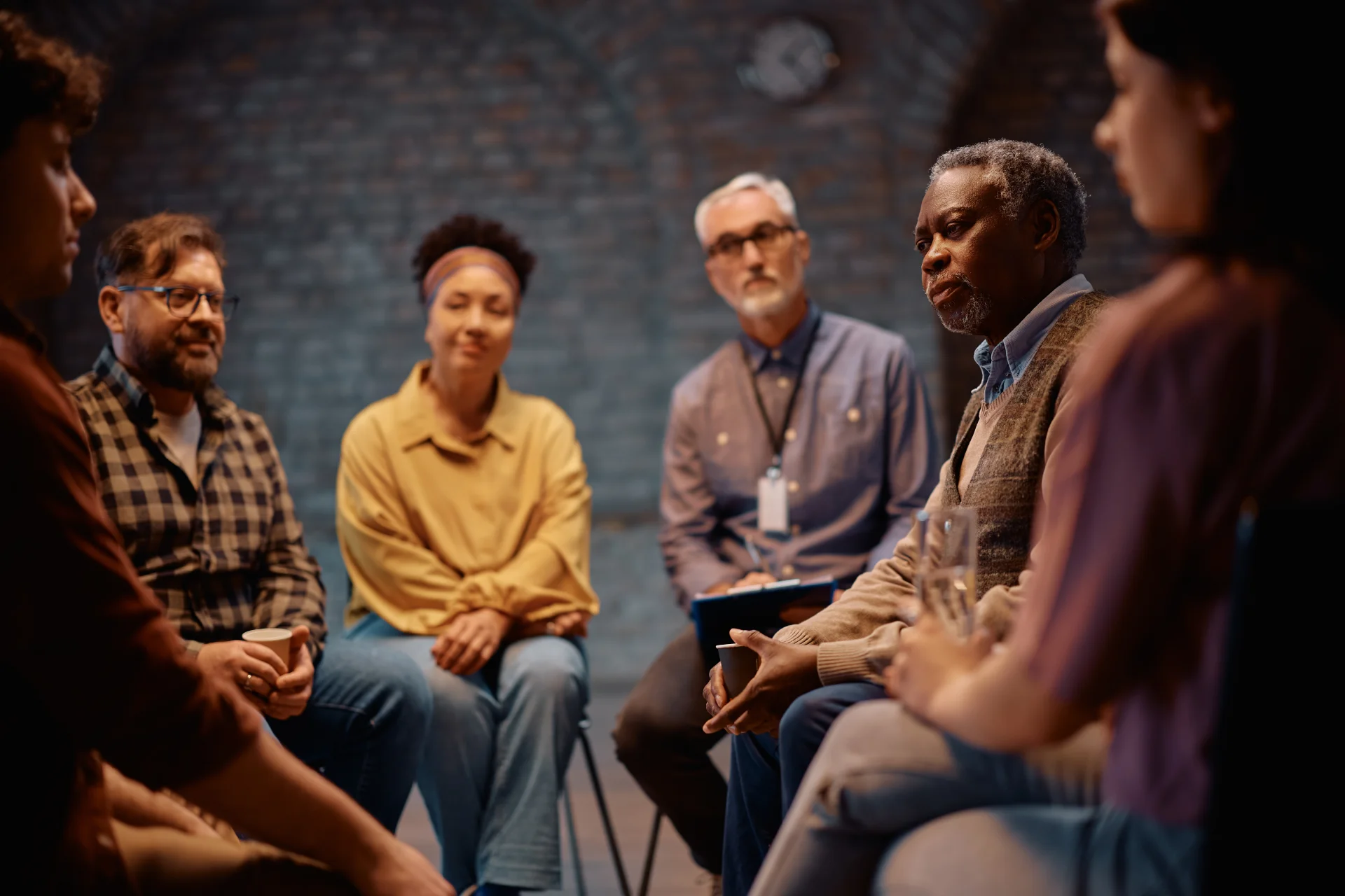 Group therapy session with diverse participants engaged in discussion, emphasizing support and connection in addiction recovery.