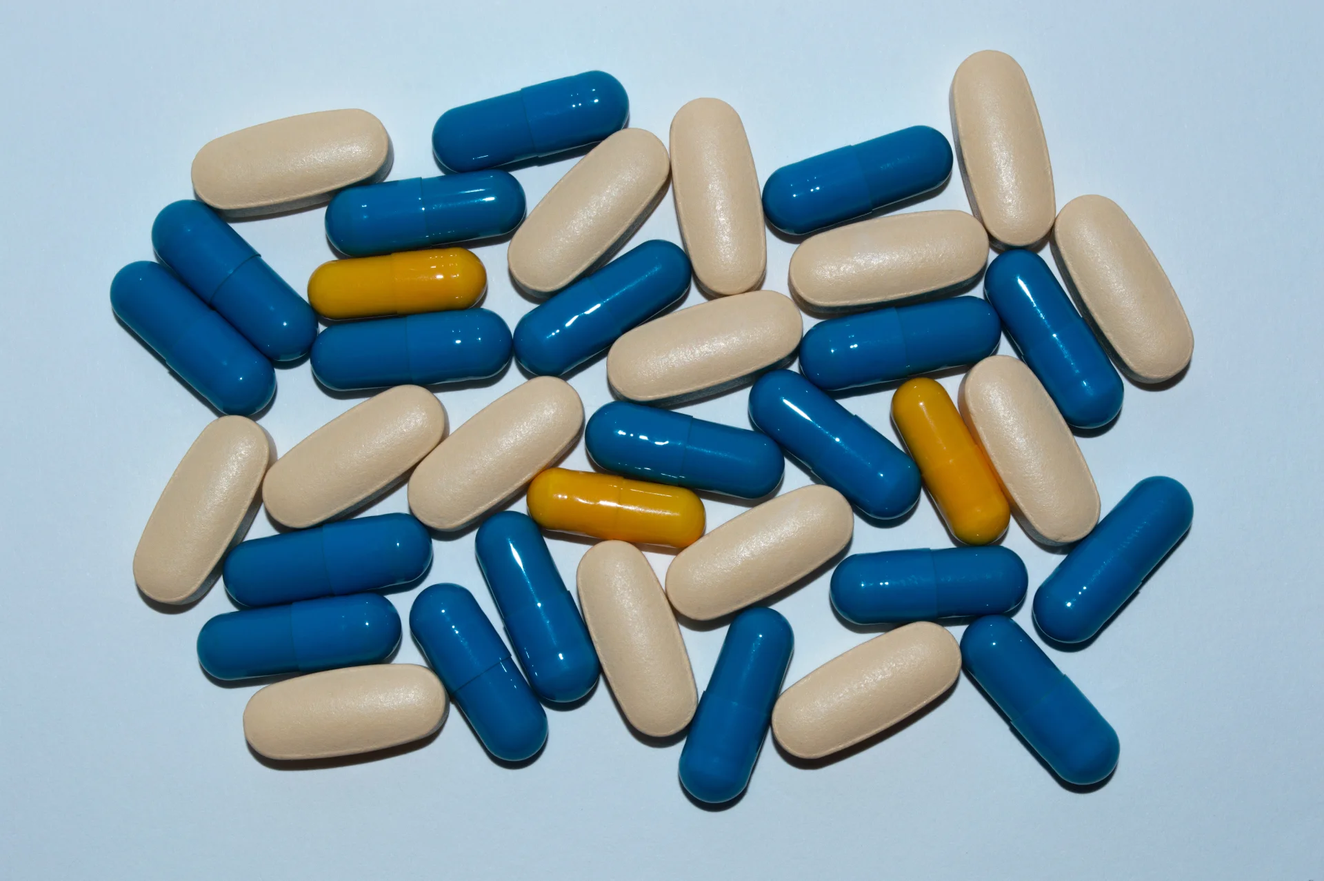 Assorted capsules in blue, beige, and yellow colors, representing prescription medications associated with addiction risks on Long Island.