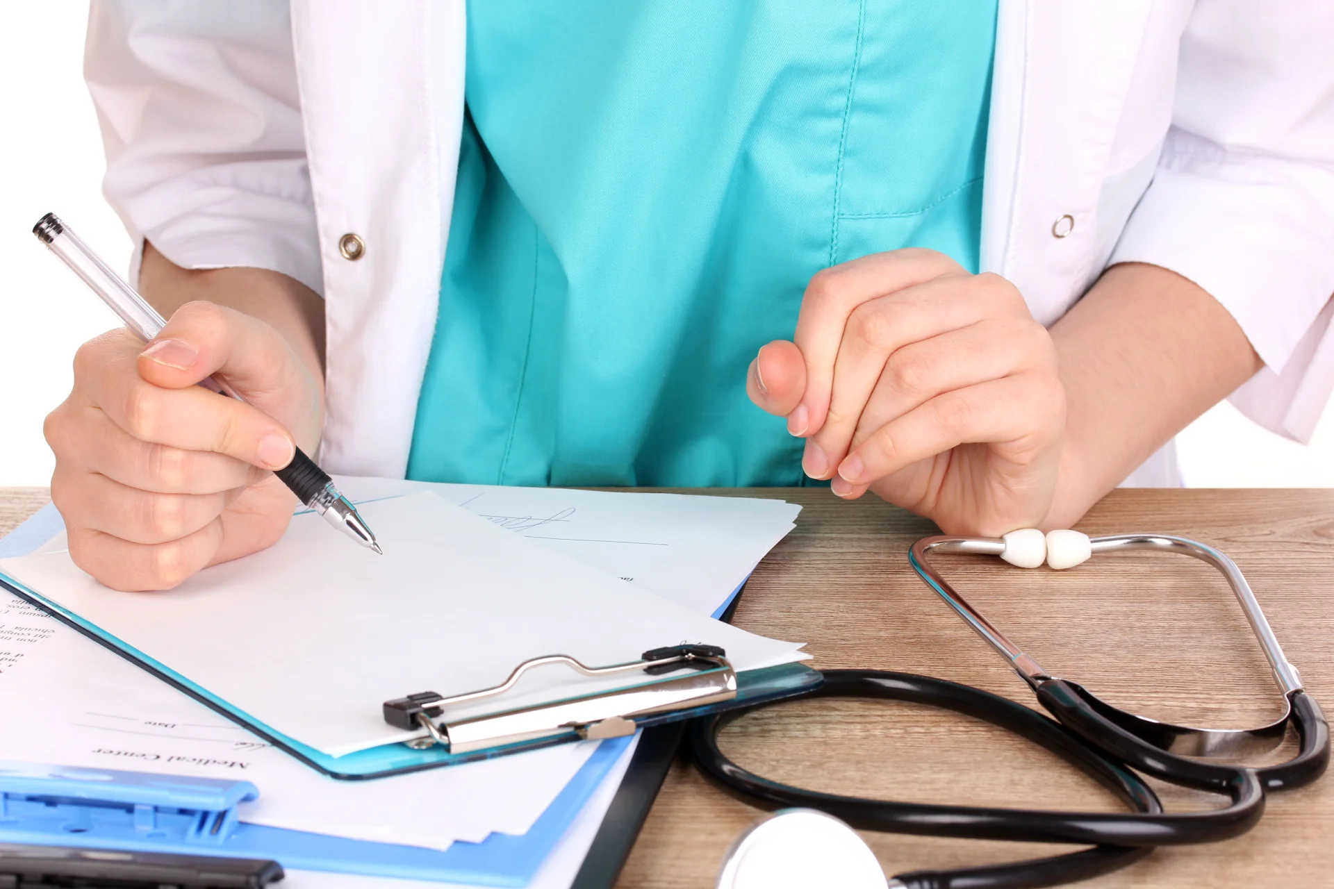 Doctor writing a treatment plan on clipboard with stethoscope and medical documents, emphasizing personalized care for addiction recovery.