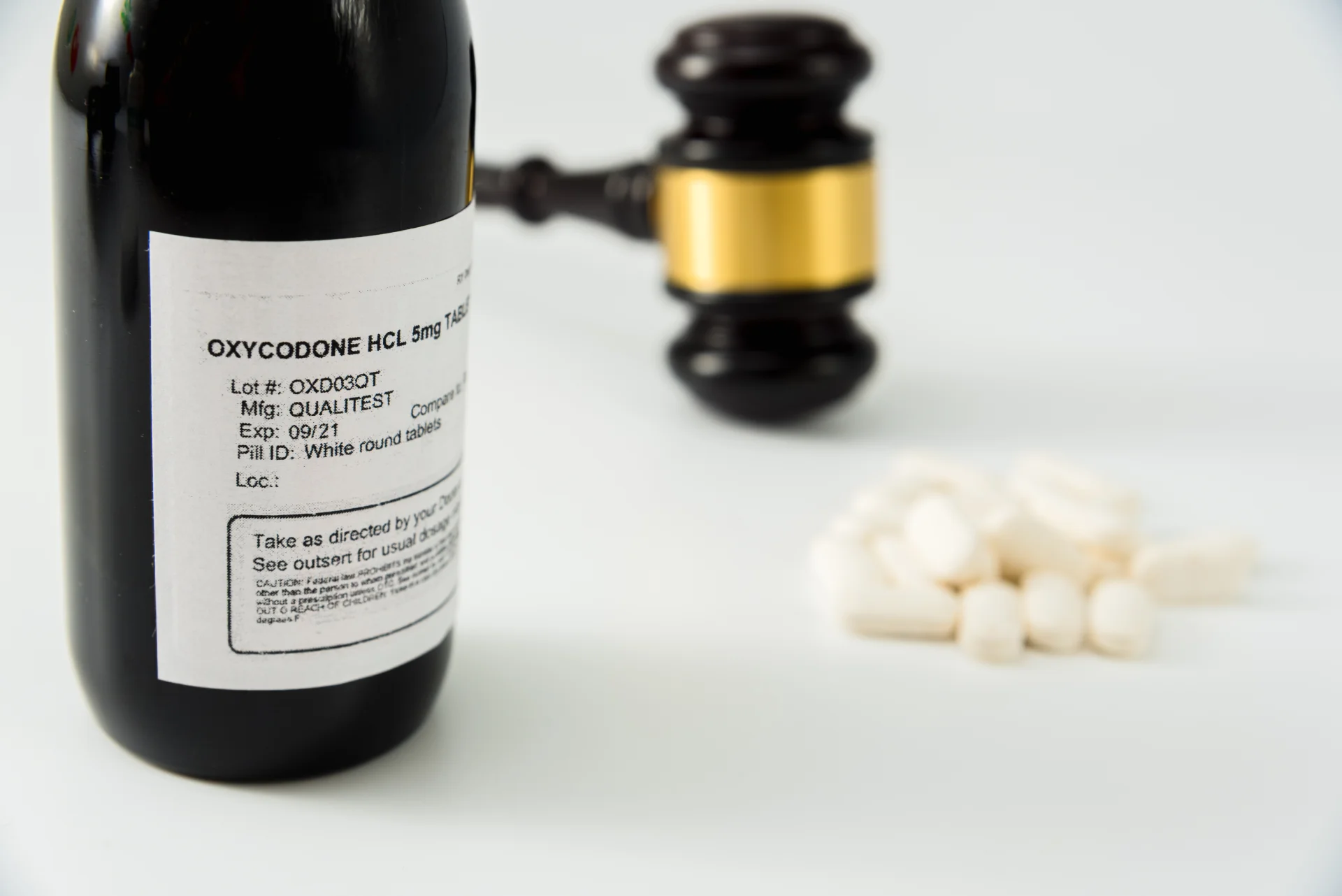 Oxycodone prescription bottle with label, 5mg tablets, and gavel, symbolizing legal and health implications of opioid addiction treatment on Long Island.
