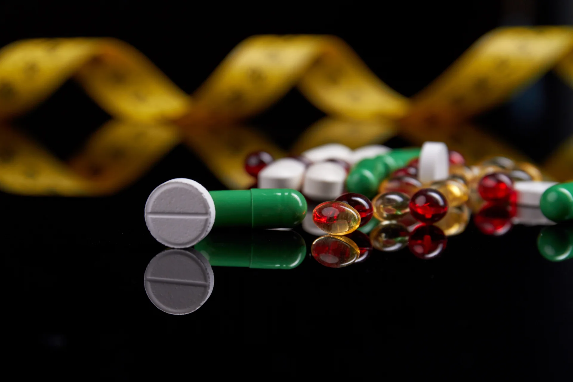 Pills including green capsules, white tablets, and red and yellow gel capsules on a reflective surface, symbolizing medication and addiction treatment related to Ativan (lorazepam).