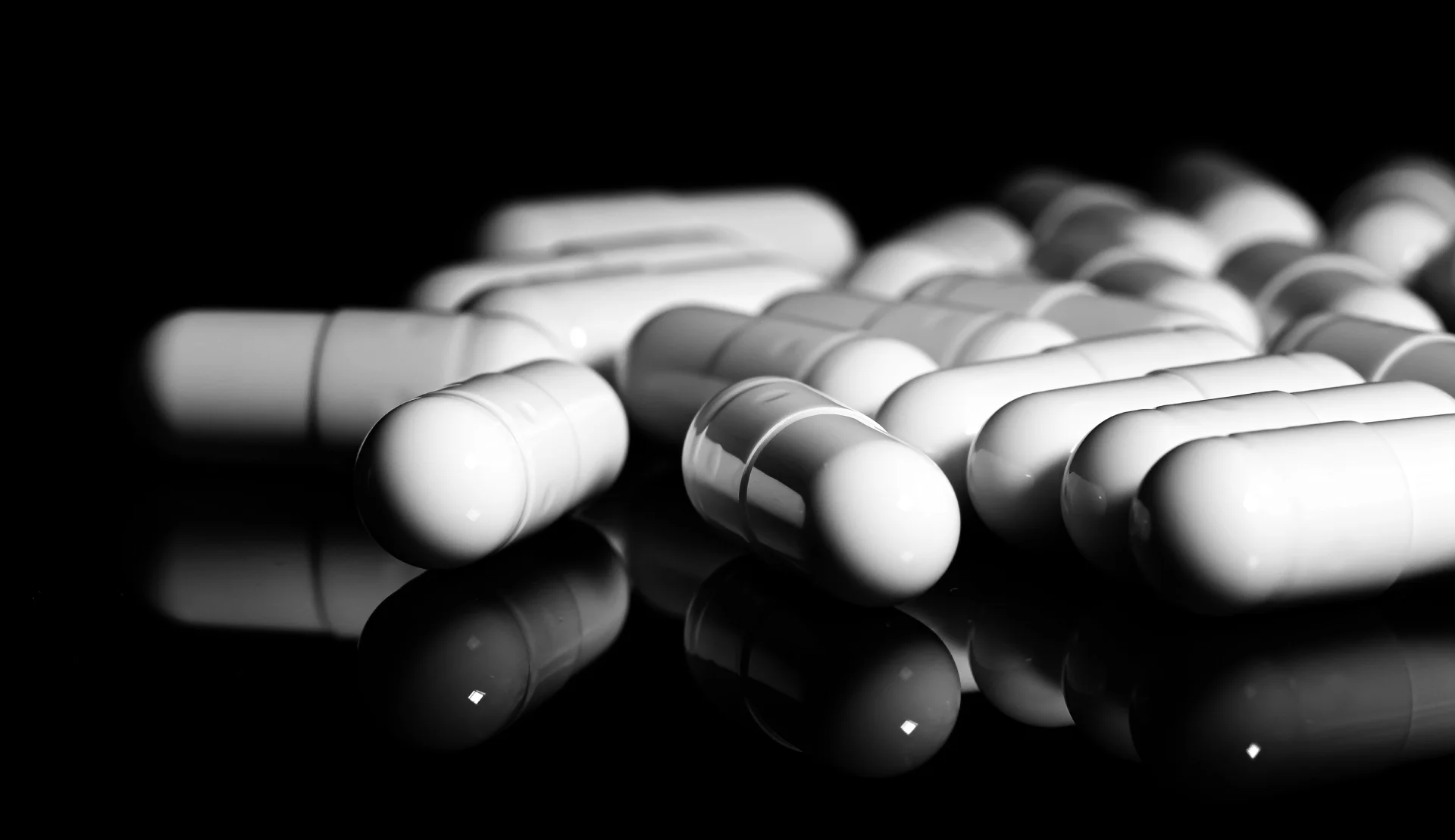 White capsules reflecting on a dark surface, representing medications like Librium for treating anxiety and alcohol withdrawal.