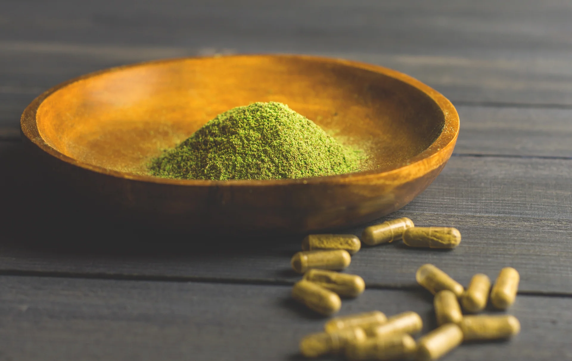 Kratom powder in wooden bowl with capsules, highlighting kratom's use in addiction treatment and detox options on Long Island.