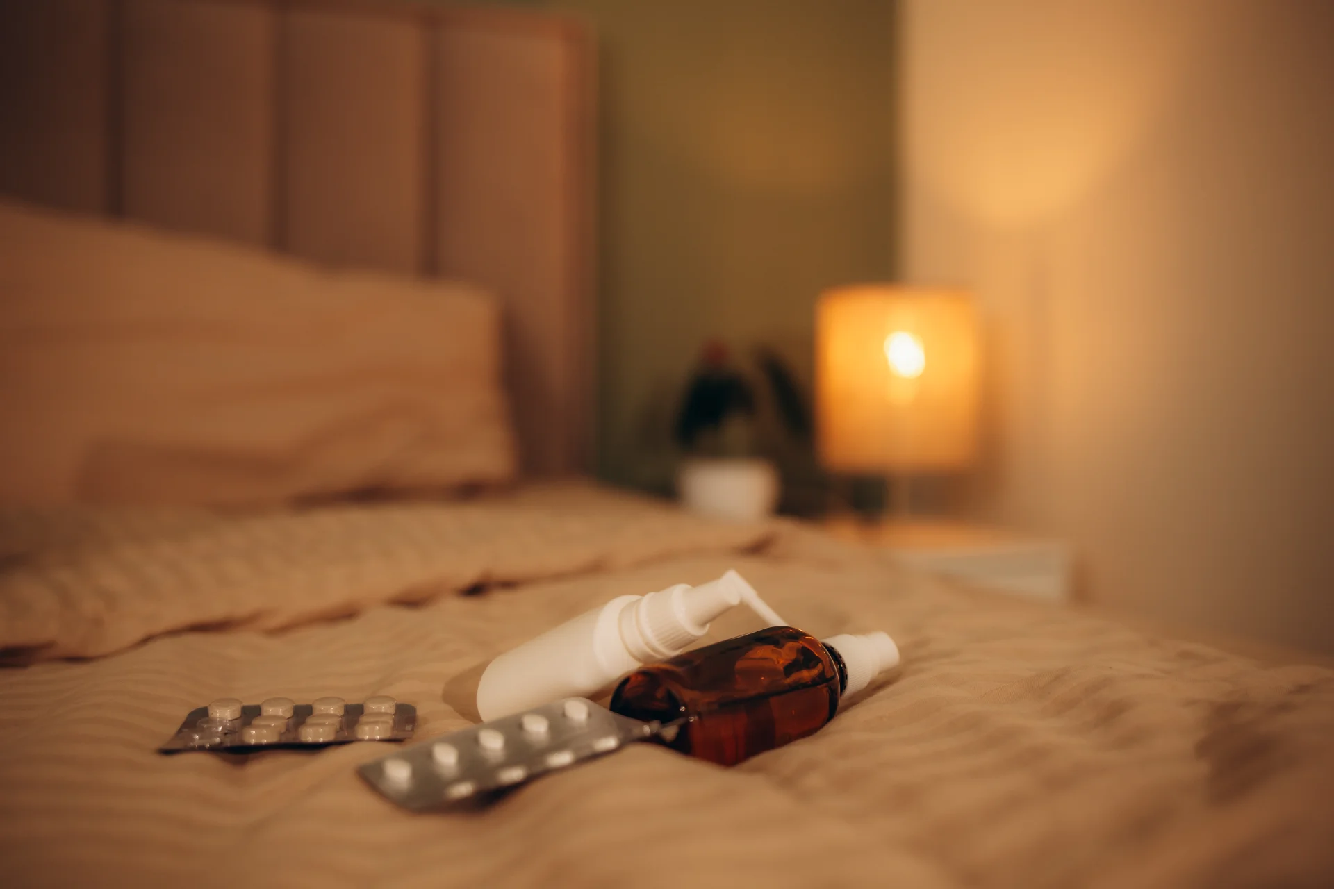Medications including pill blister pack, amber bottle, and spray bottle on a bed, highlighting concerns related to Halcion (triazolam) use and addiction recovery resources.