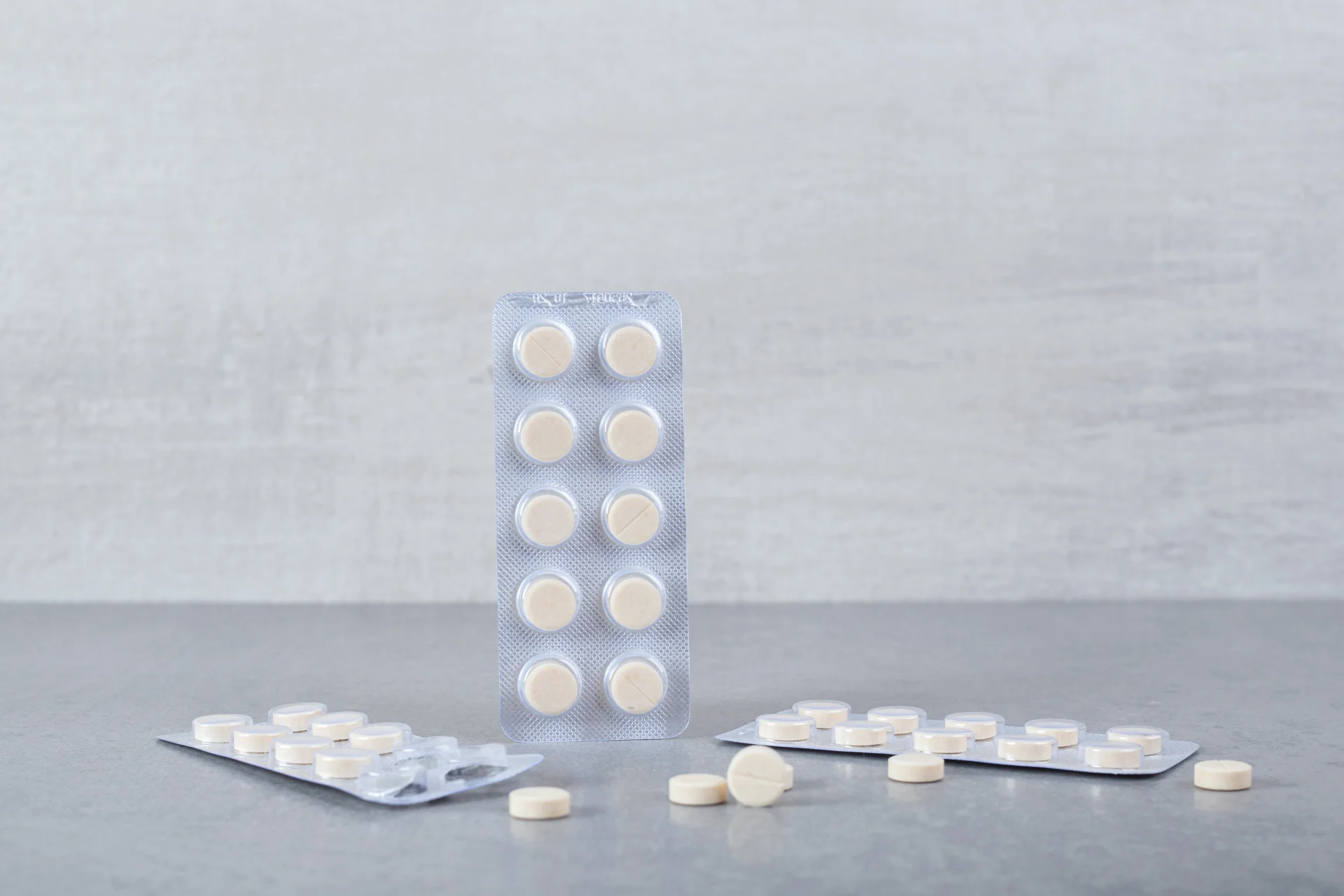 Clonidine tablets in blister pack and scattered on surface, representing medication for hypertension and withdrawal symptom relief.