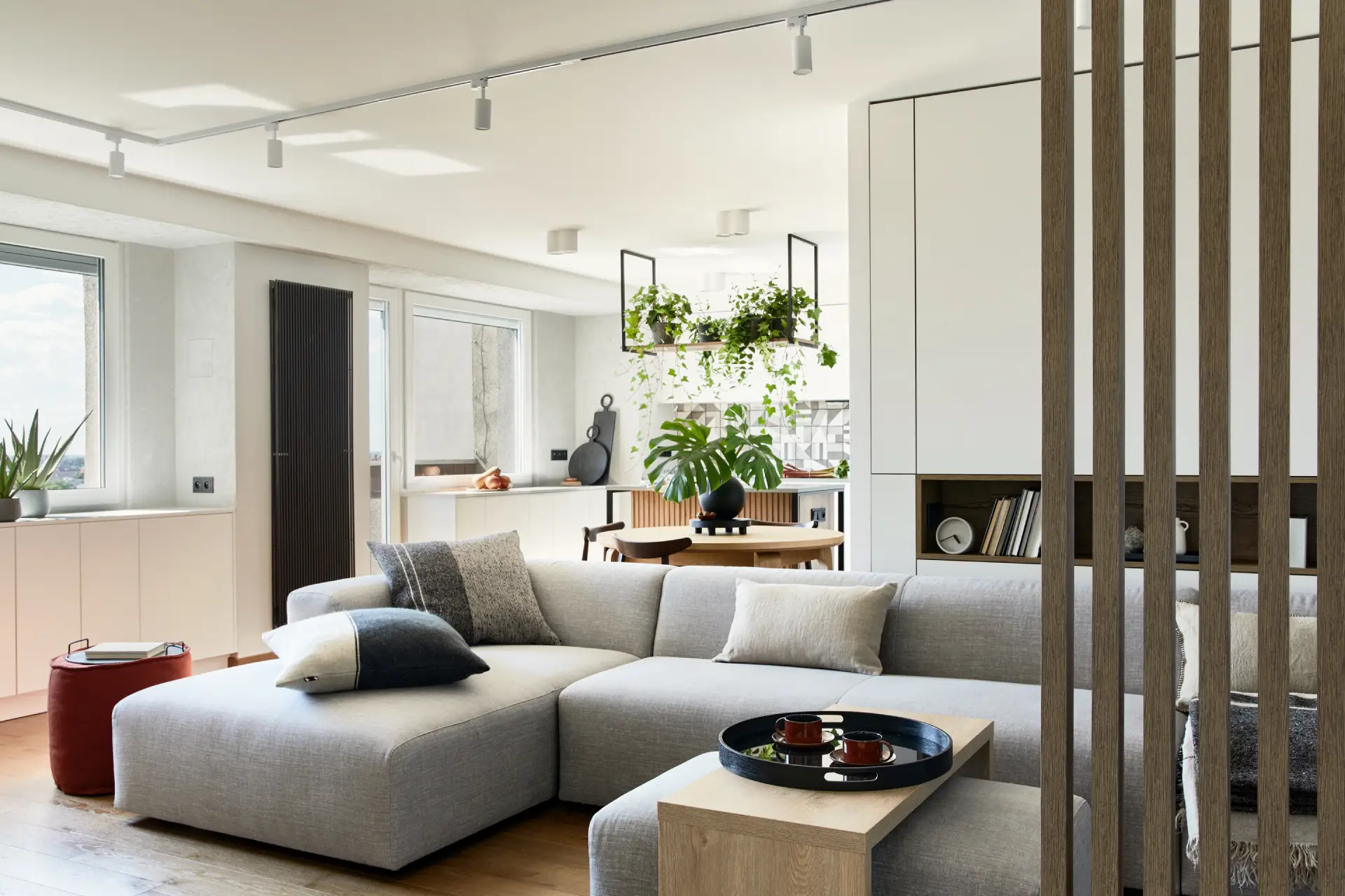 Stylish living room interior with a gray sectional sofa, decorative pillows, wooden coffee table with tea cups, and greenery, emphasizing a calming and supportive environment for recovery and mental health.
