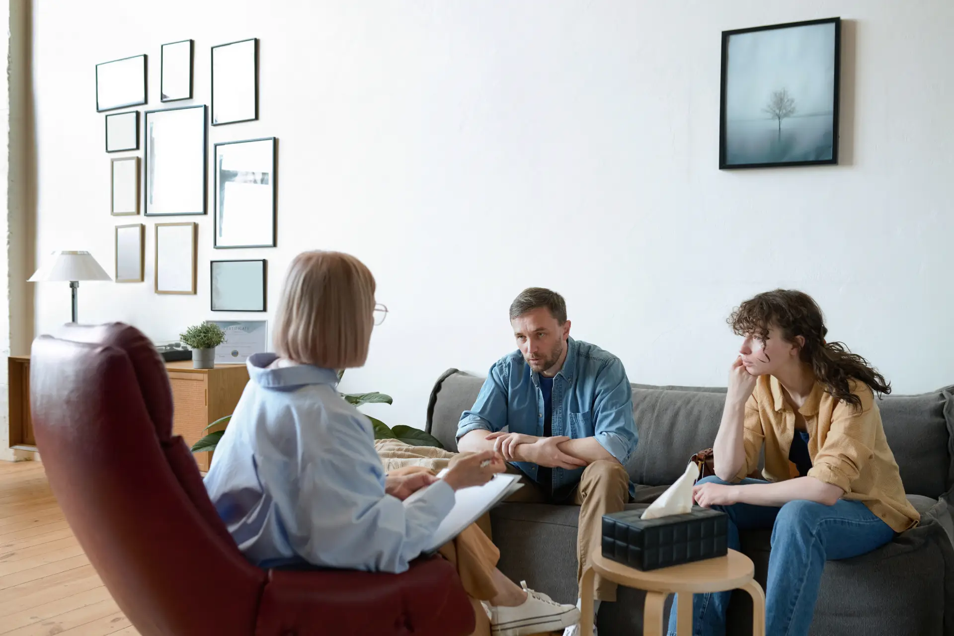 Young couple engaged in therapy session with therapist, discussing substance use recovery and mental health strategies in a comfortable counseling environment.